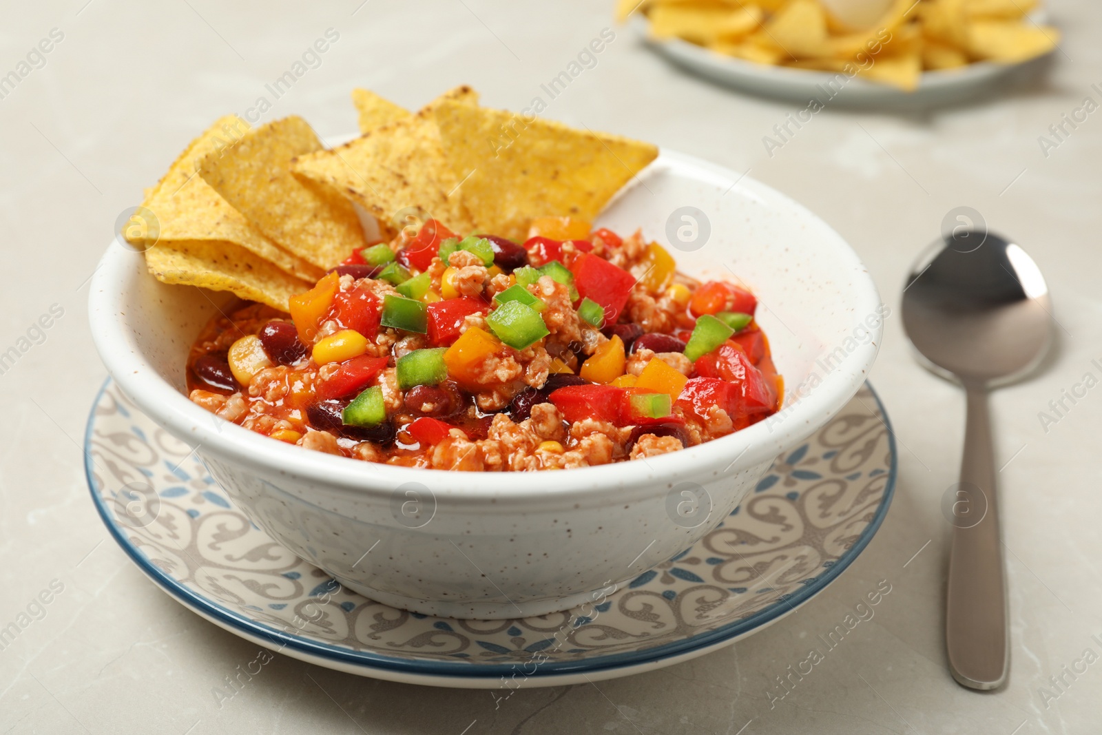 Photo of Chili con carne served with tortilla chips in bowl on table