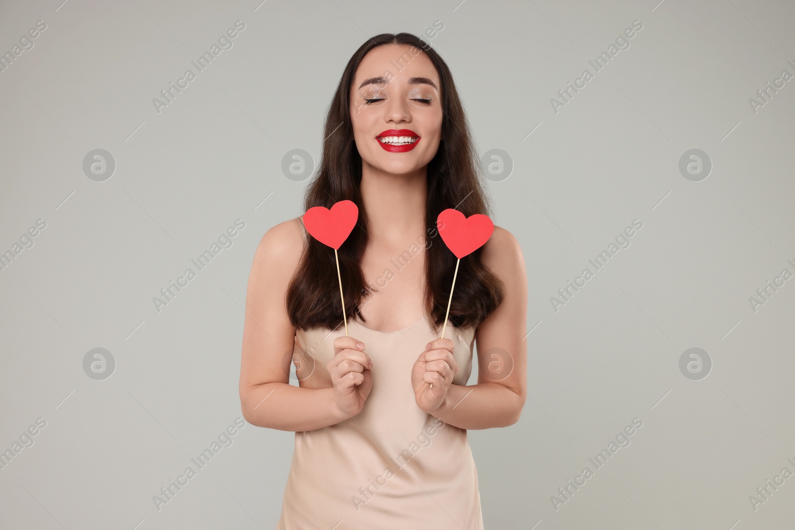 Photo of Beautiful young woman with paper hearts on grey background