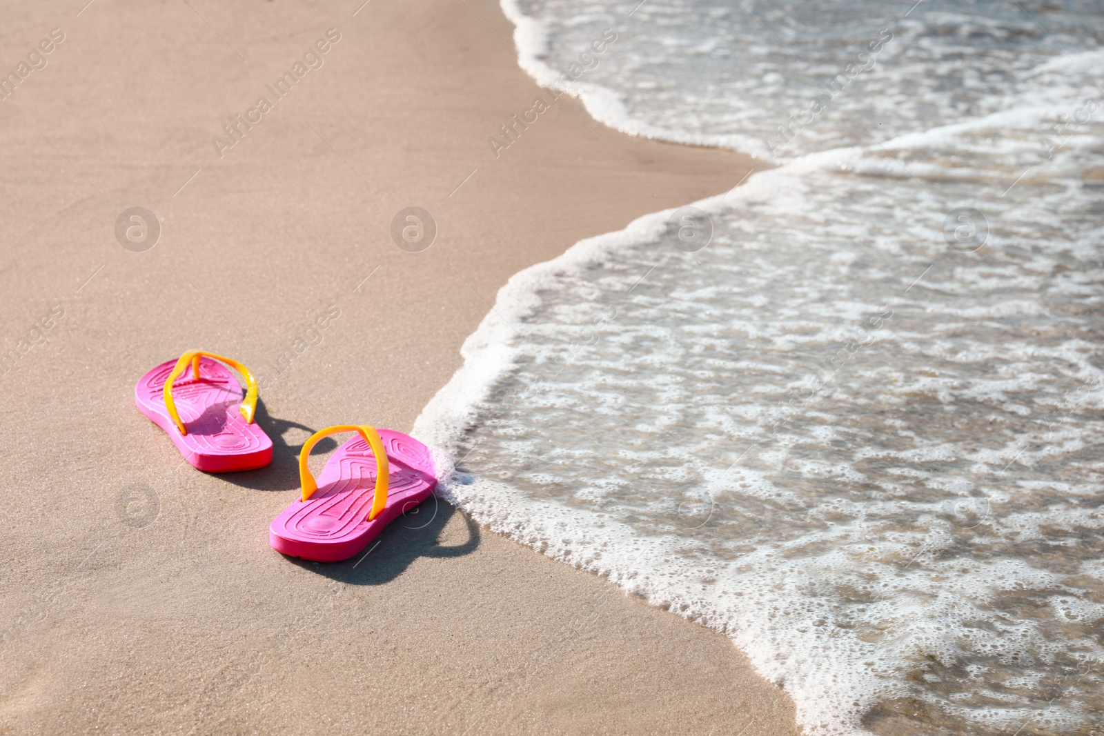 Photo of Pair of stylish flip flops on beach