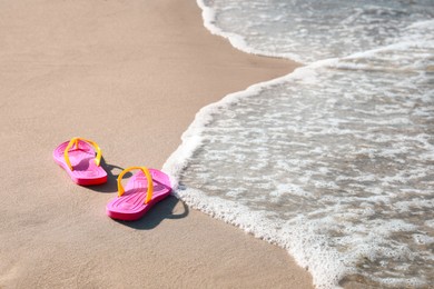 Photo of Pair of stylish flip flops on beach