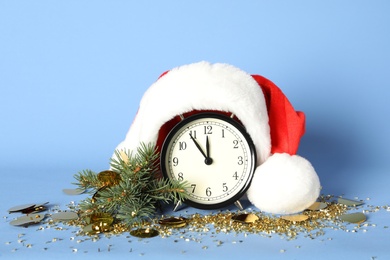 Photo of Vintage alarm clock with Christmas decor on light blue background. New Year countdown