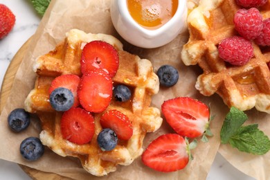 Photo of Delicious Belgian waffles with fresh berries and honey on table, top view