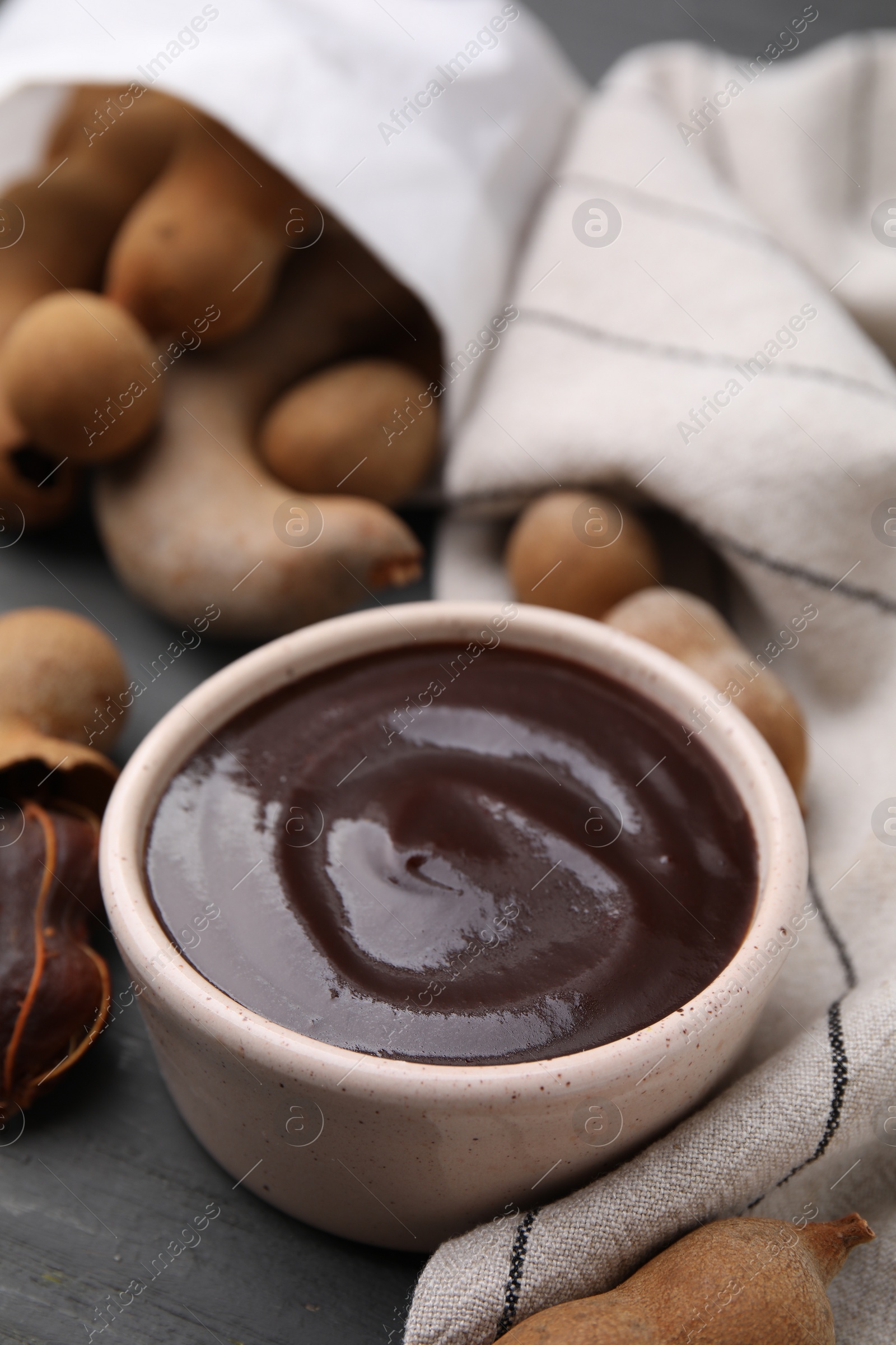 Bowl of tamarind sauce and fresh pods on table Photo of Bowl of tamarind sauce and fresh pods on table
