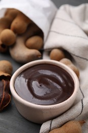 Photo of Bowl of tamarind sauce and fresh pods on table