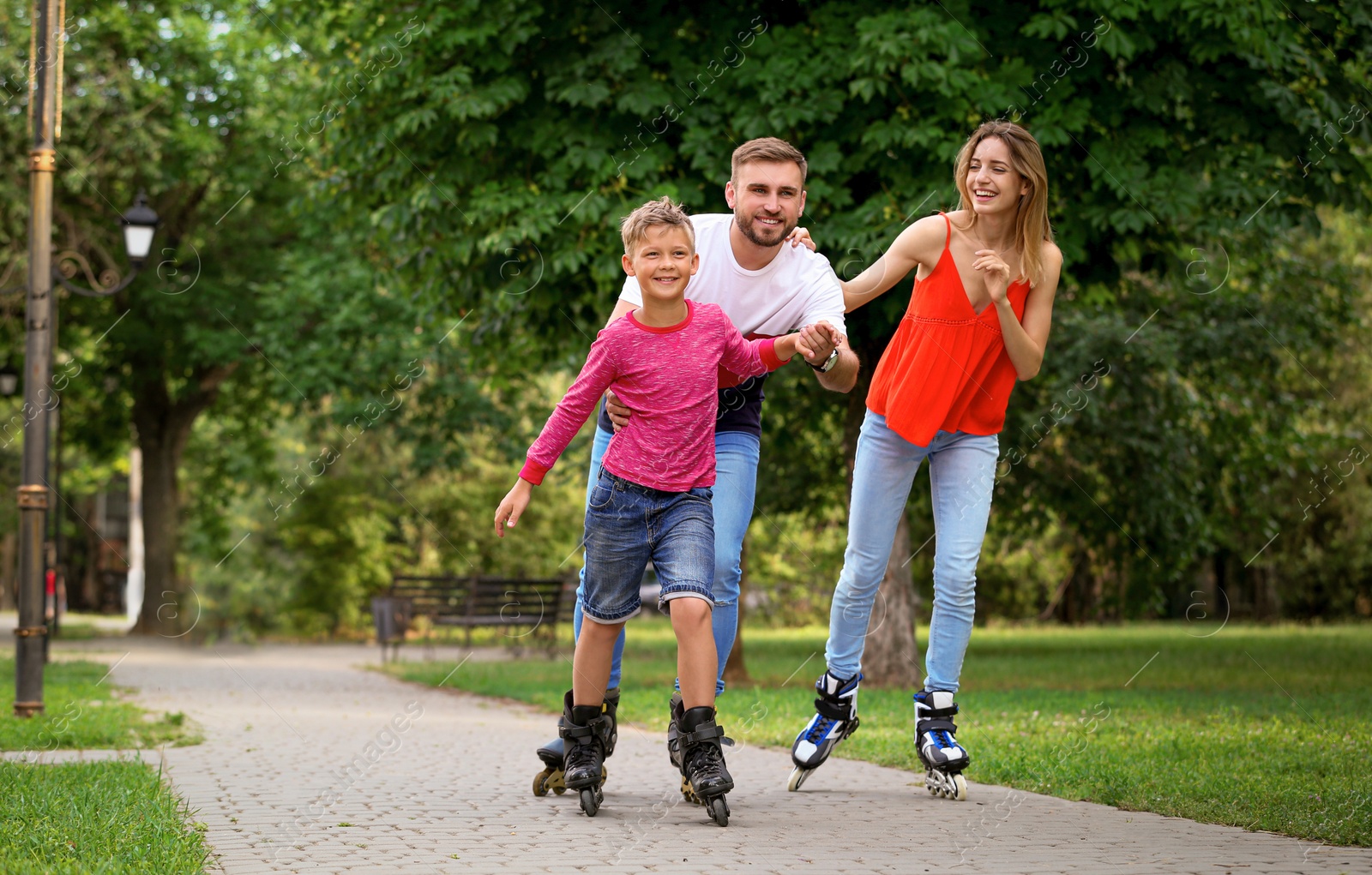 Photo of Young happy family roller skating in summer park