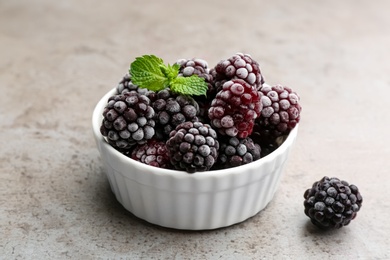 Photo of Tasty frozen blackberries with mint on grey table