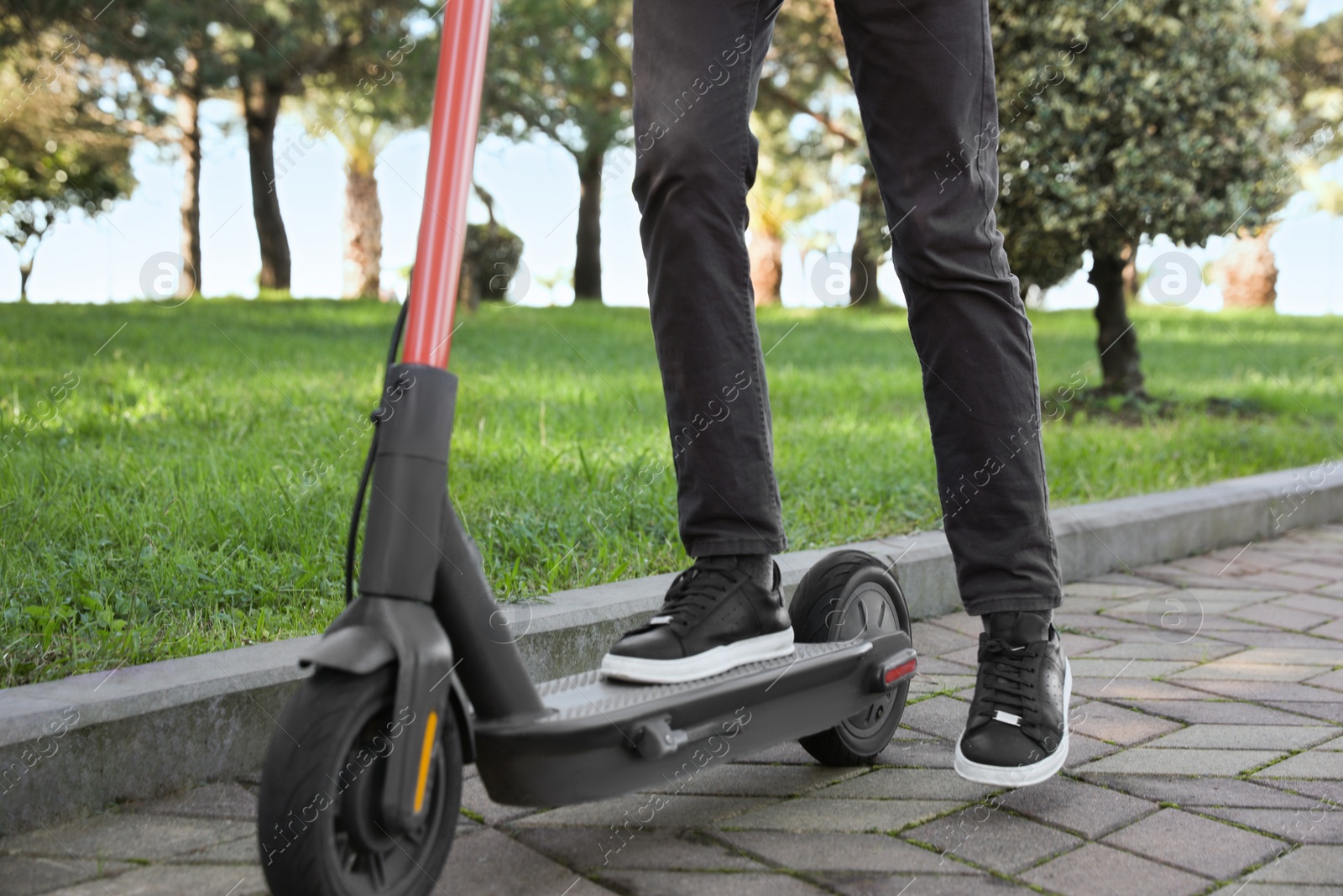 Photo of Man riding modern electric scooter in park, closeup