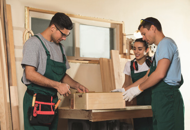 Photo of Professional carpenters with wooden crate in workshop