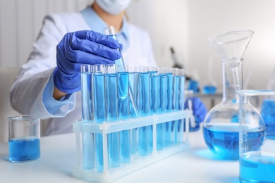 Doctor taking test tube with blue liquid, closeup. Laboratory analysis