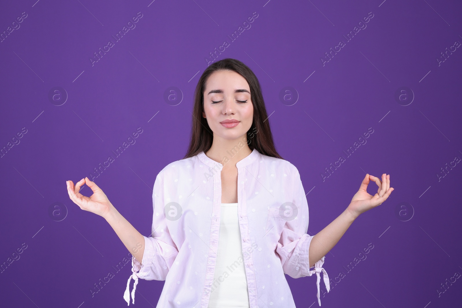 Photo of Young woman meditating on purple background. Stress relief exercise