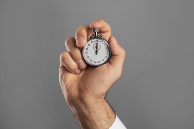 Man holding vintage timer on grey background, closeup