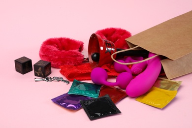 Photo of Shopping bag and different sex toys on pink background