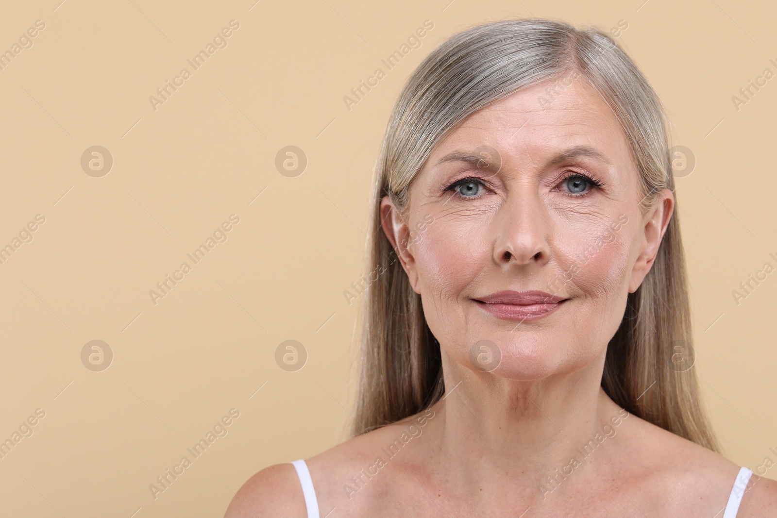 Photo of Portrait of beautiful senior woman on beige background. Space for text