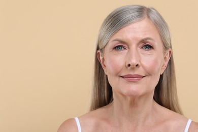 Portrait of beautiful senior woman on beige background. Space for text