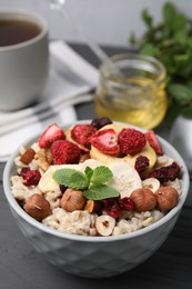 Photo of Oatmeal with freeze dried fruits, nuts and mint on grey table