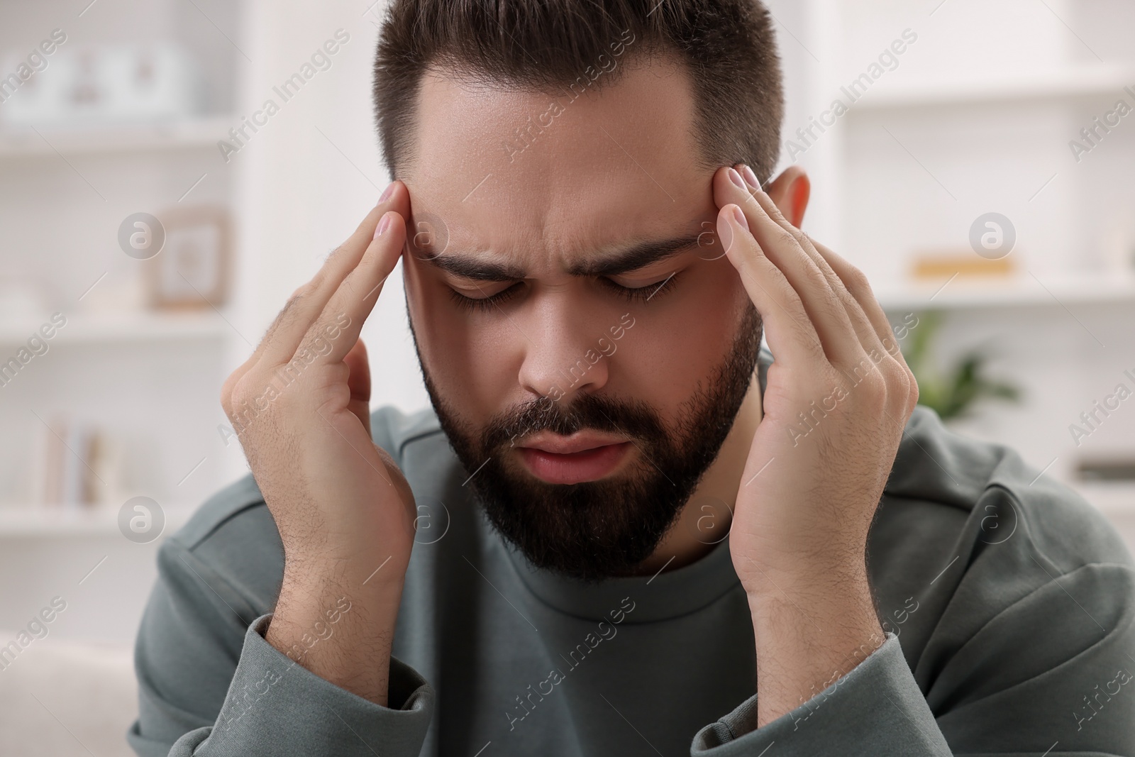 Photo of Man suffering from headache at home, closeup