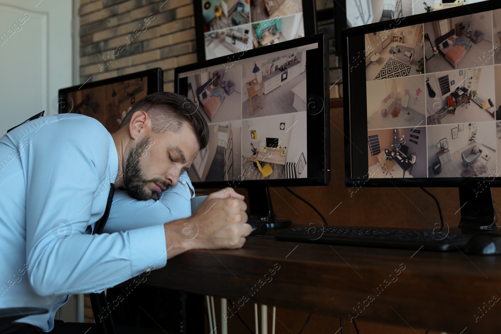 Photo of Male security guard sleeping at workplace. CCTV surveillance