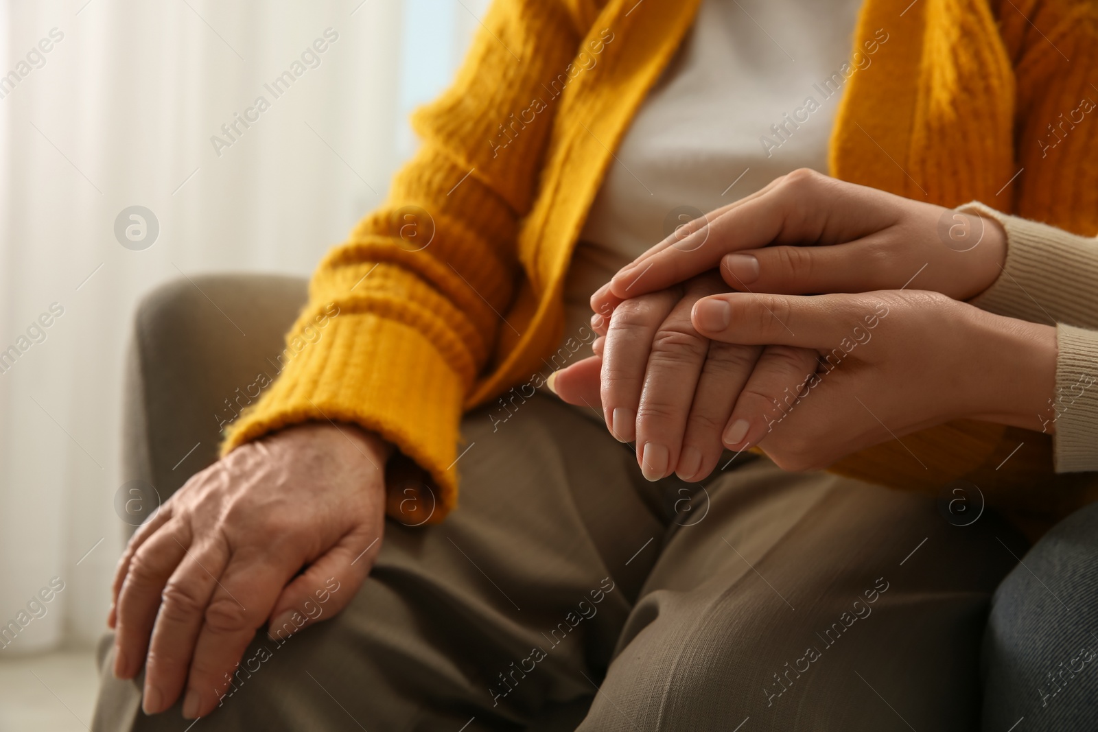 Photo of Young and elderly women holding hands together indoors, closeup. Space for text