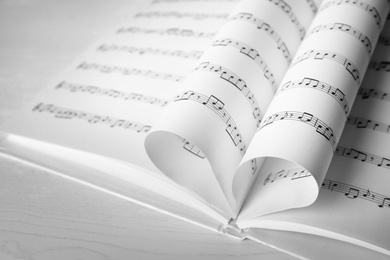 Heart made of book pages with music notes on table, closeup. Space for text