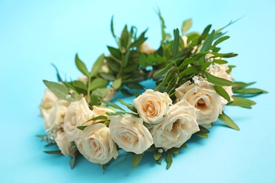 Wreath made of beautiful flowers on light blue background, closeup