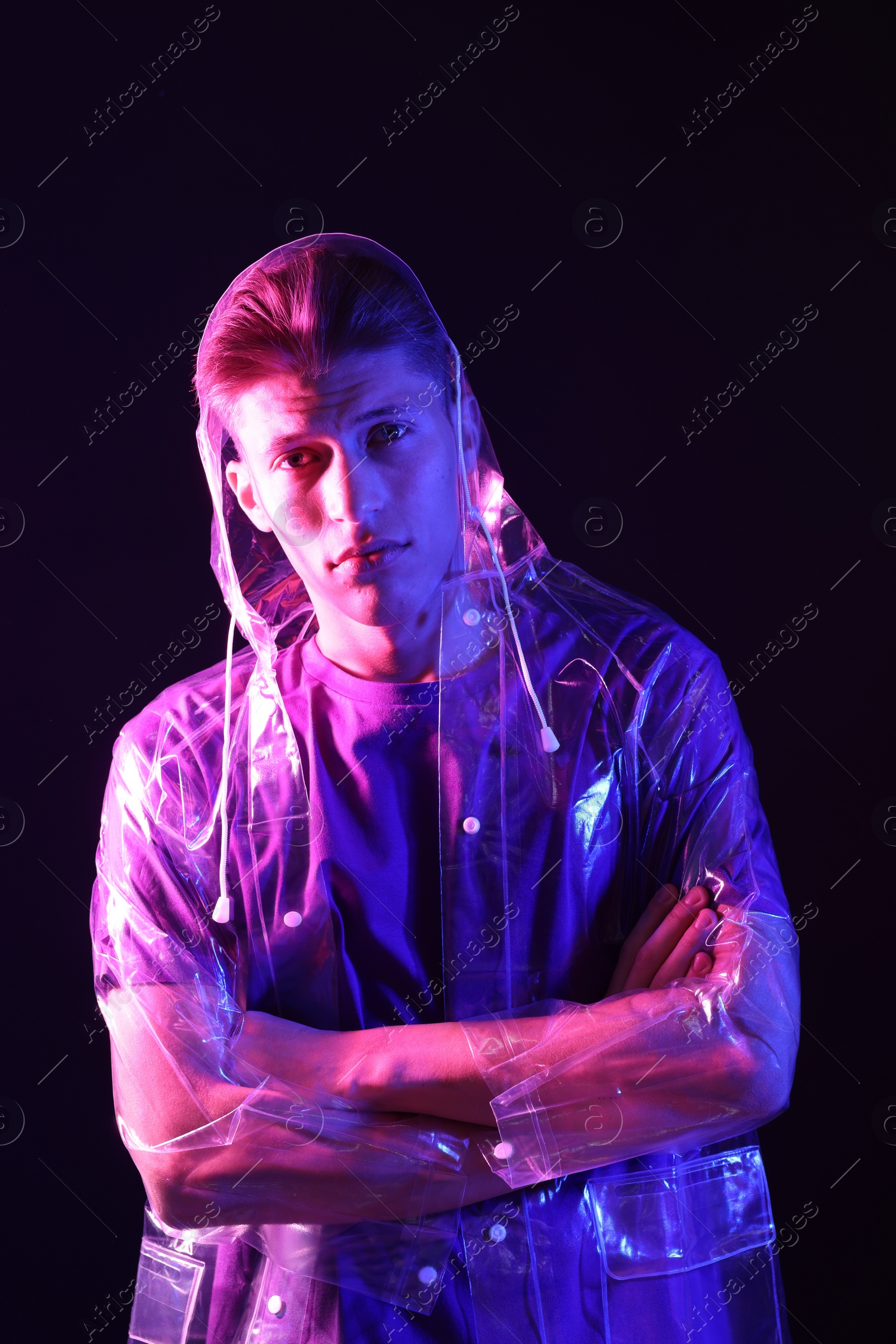 Photo of Young man wearing clear coat on dark background in neon lights