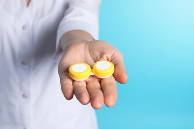 Photo of Female doctor holding contact lens case on color background, closeup view with space for text. Medical object