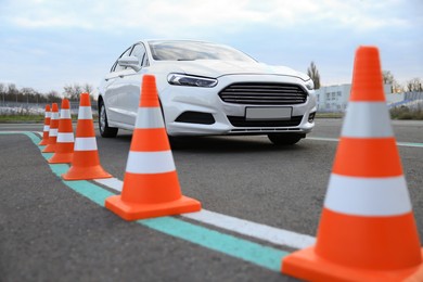Photo of Modern car on test track with traffic cones, low angle view. Driving school