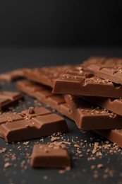 Pieces of tasty chocolate bars on grey table, closeup