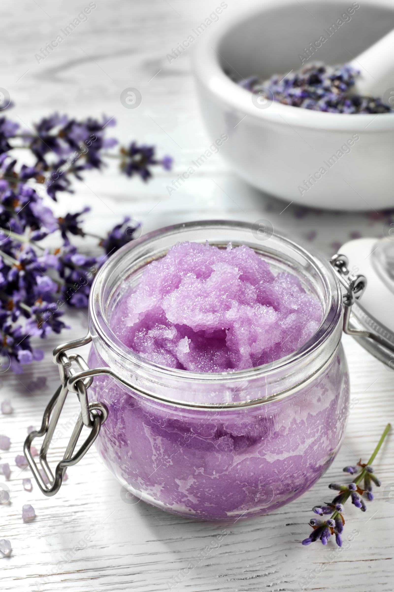 Photo of Natural sugar scrub and lavender flowers on white wooden table. Cosmetic product