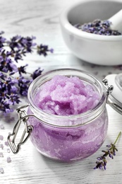 Natural sugar scrub and lavender flowers on white wooden table. Cosmetic product
