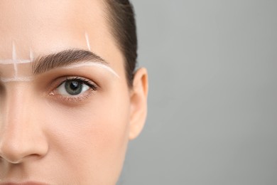 Photo of Eyebrow correction. Young woman with markings on face against grey background, closeup. Space for text