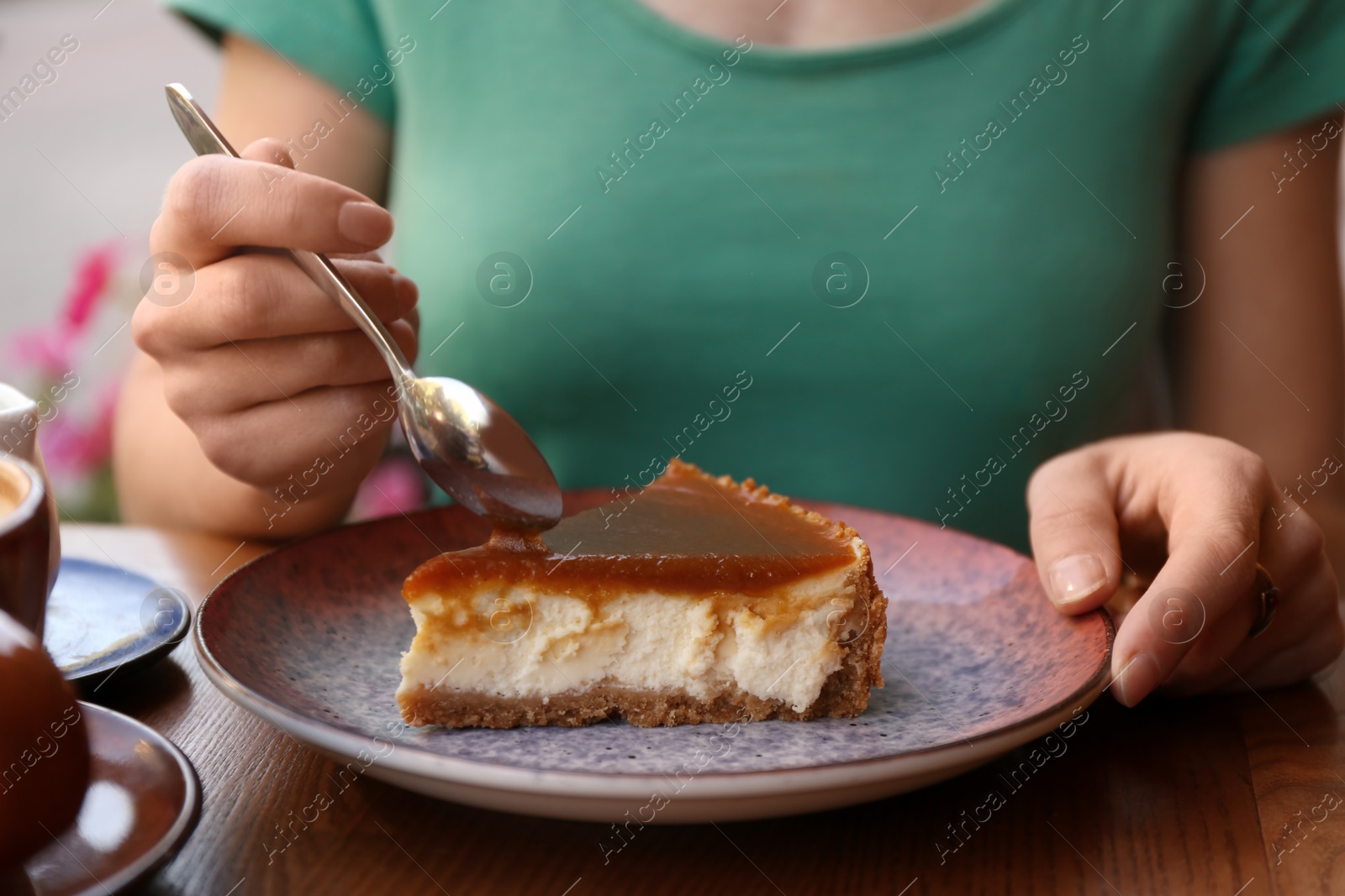 Photo of Woman eating slice of cake at table, closeup