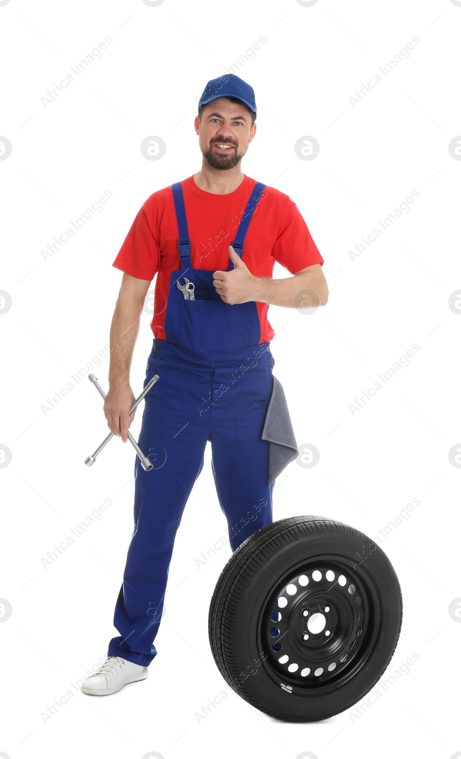 Photo of Full length portrait of professional auto mechanic with lug wrench and wheel on white background