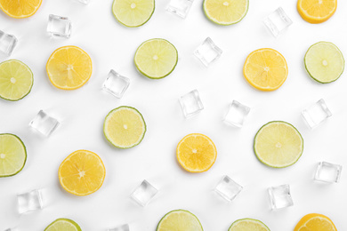 Photo of Lemonade layout with ice cubes, lime and orange slices on white background, top view