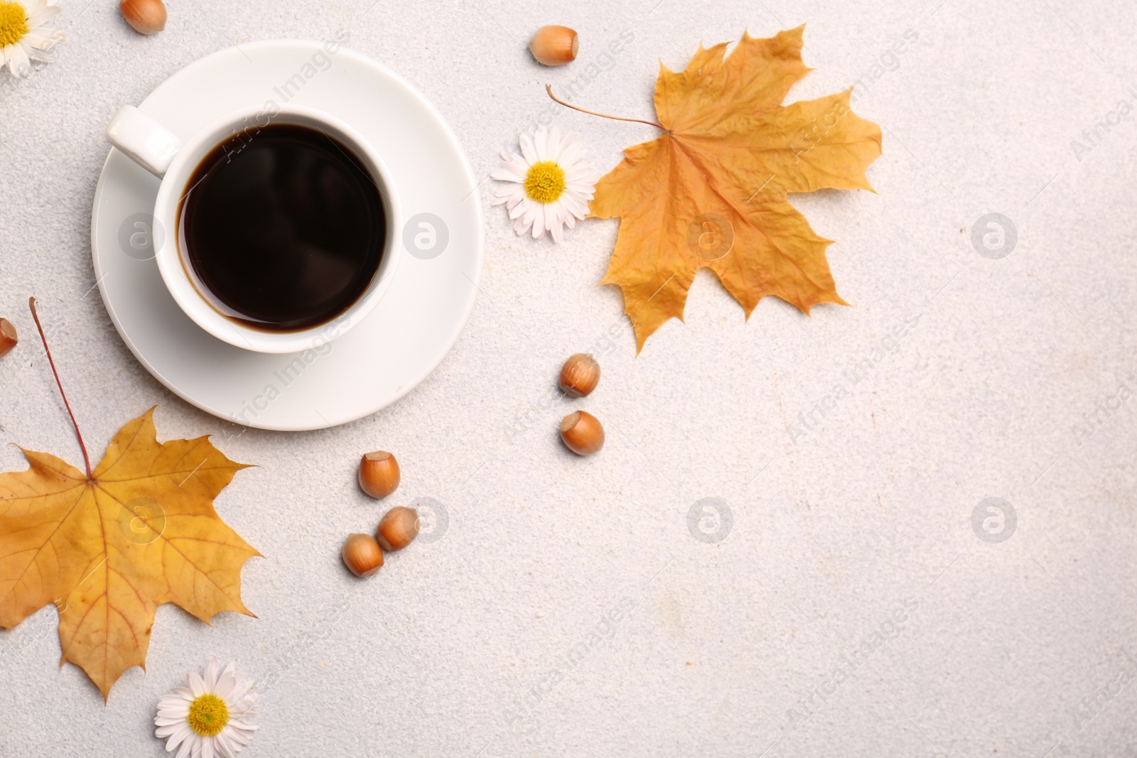 Photo of Flat lay composition with cup of hot drink and autumn leaves on light grey textured table. Space for text