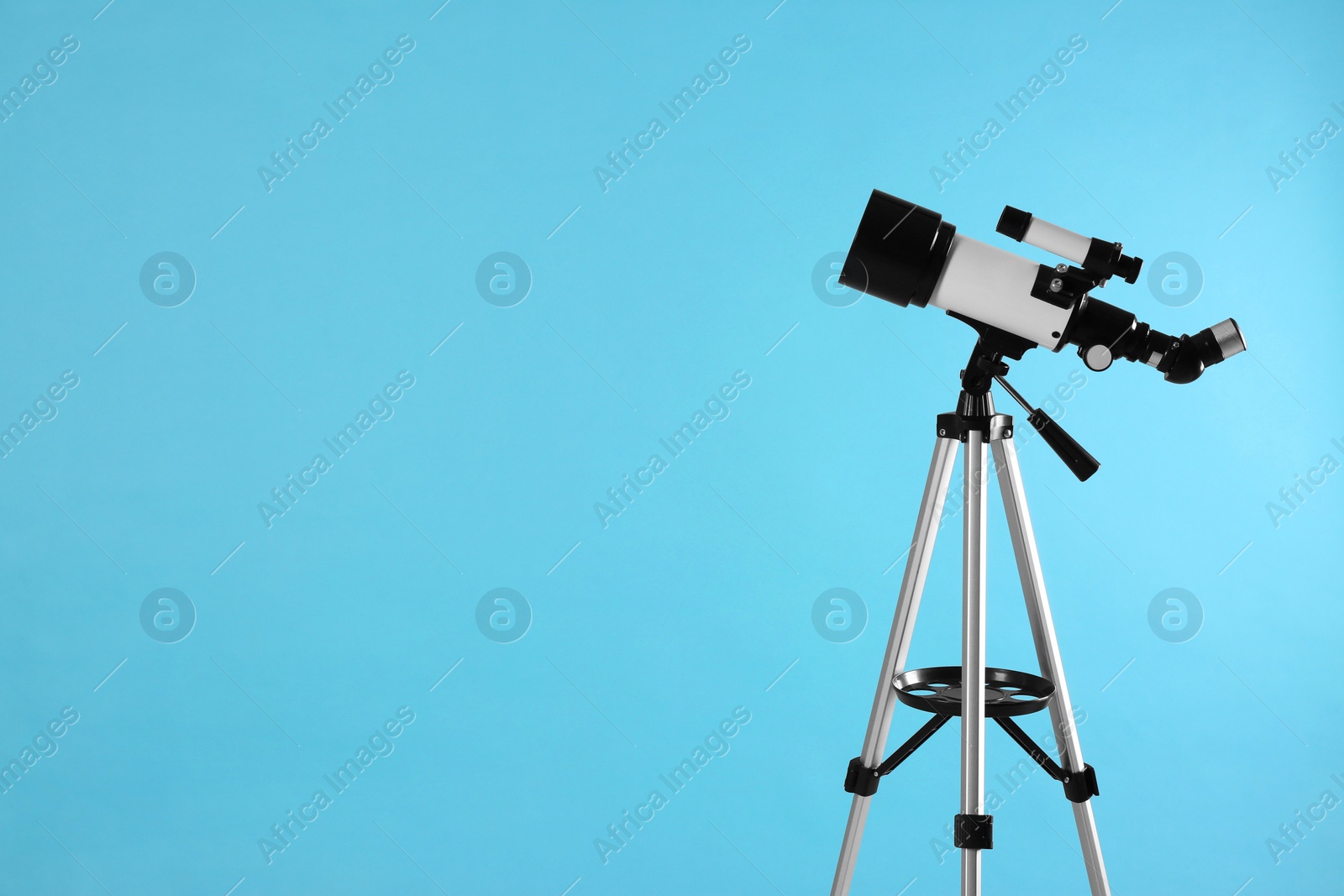 Photo of Tripod with modern telescope on light blue background, space for text