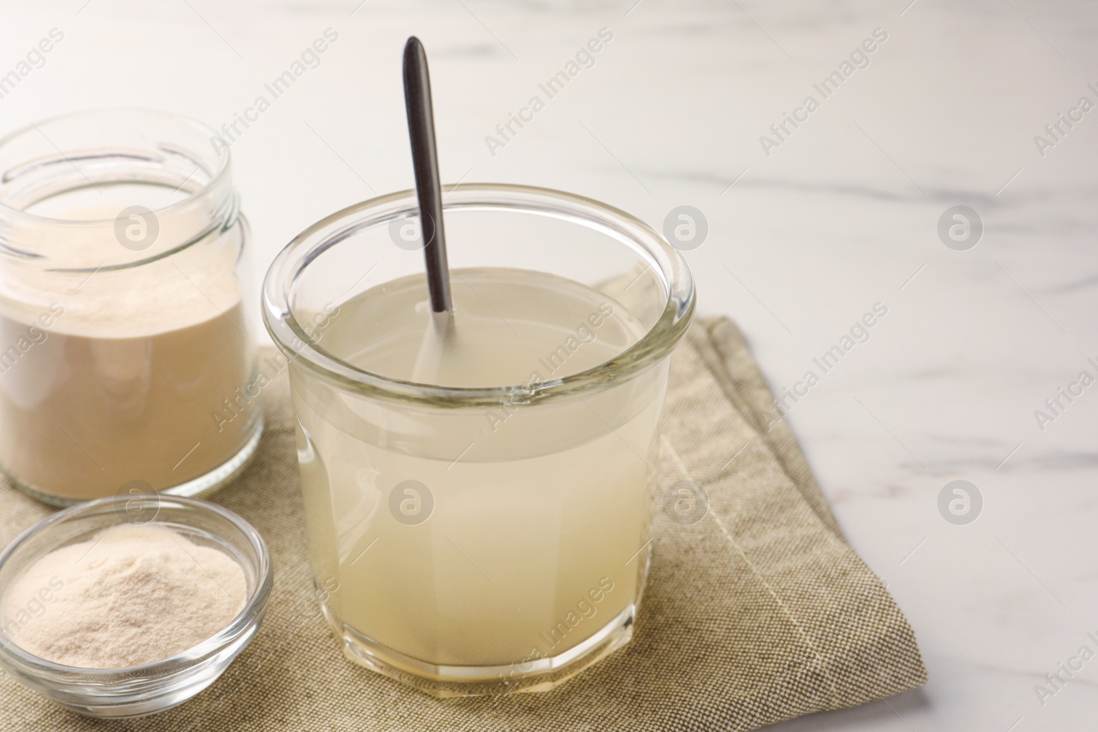 Photo of Agar-agar jelly and powder on white marble table. Space for text