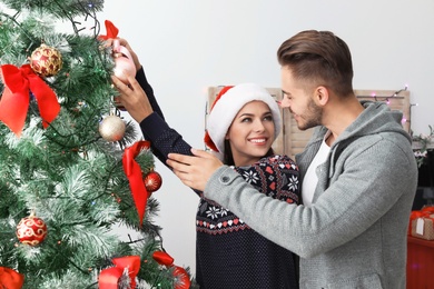 Happy young couple decorating Christmas tree together at home