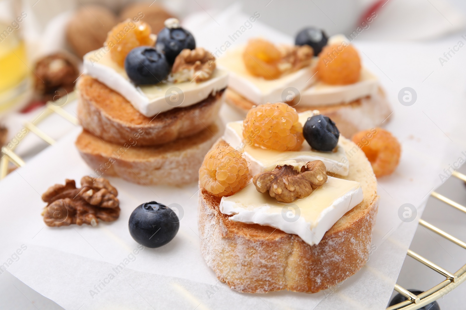 Photo of Tasty sandwiches with brie cheese, fresh berries and walnuts on table, closeup