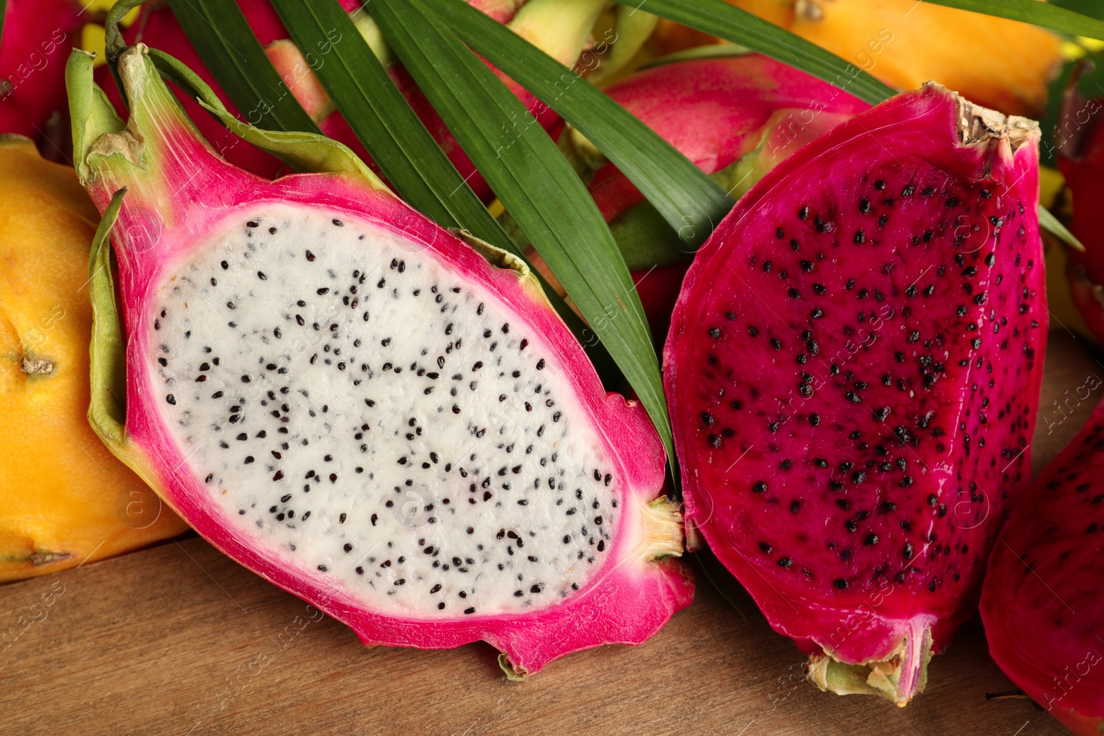 Photo of Different cut pitahaya fruits on wooden board, closeup