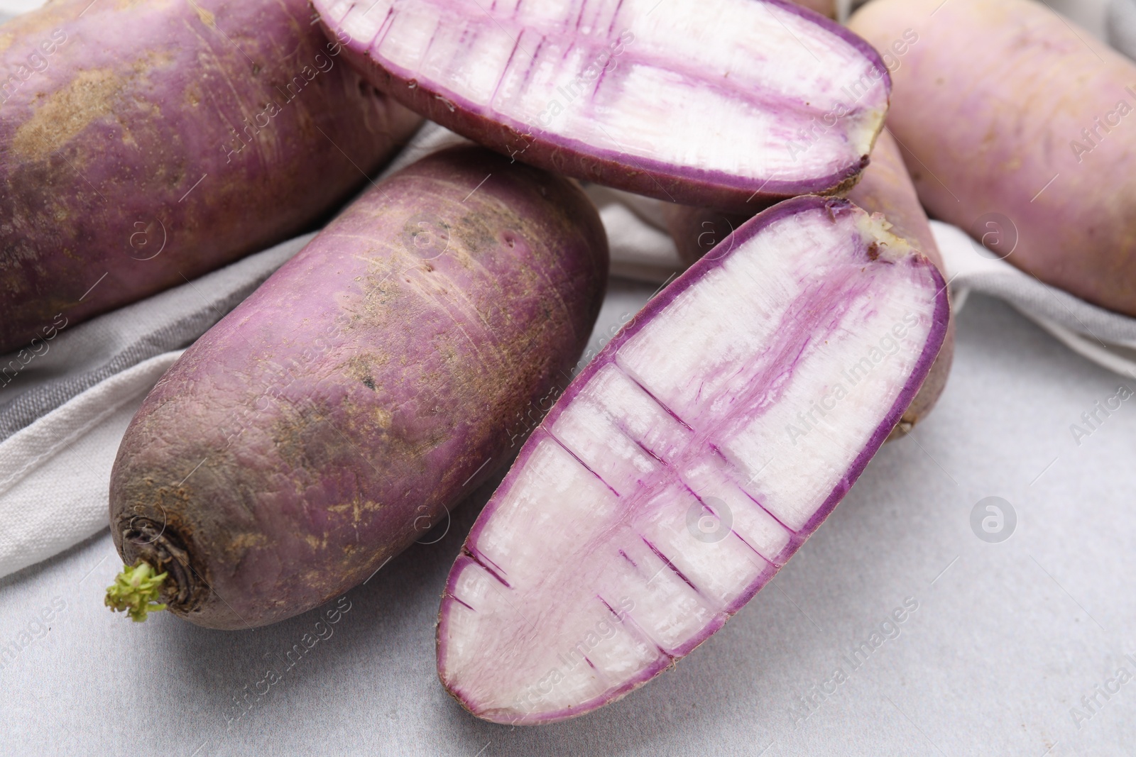 Photo of Purple daikon radishes on light grey table, closeup