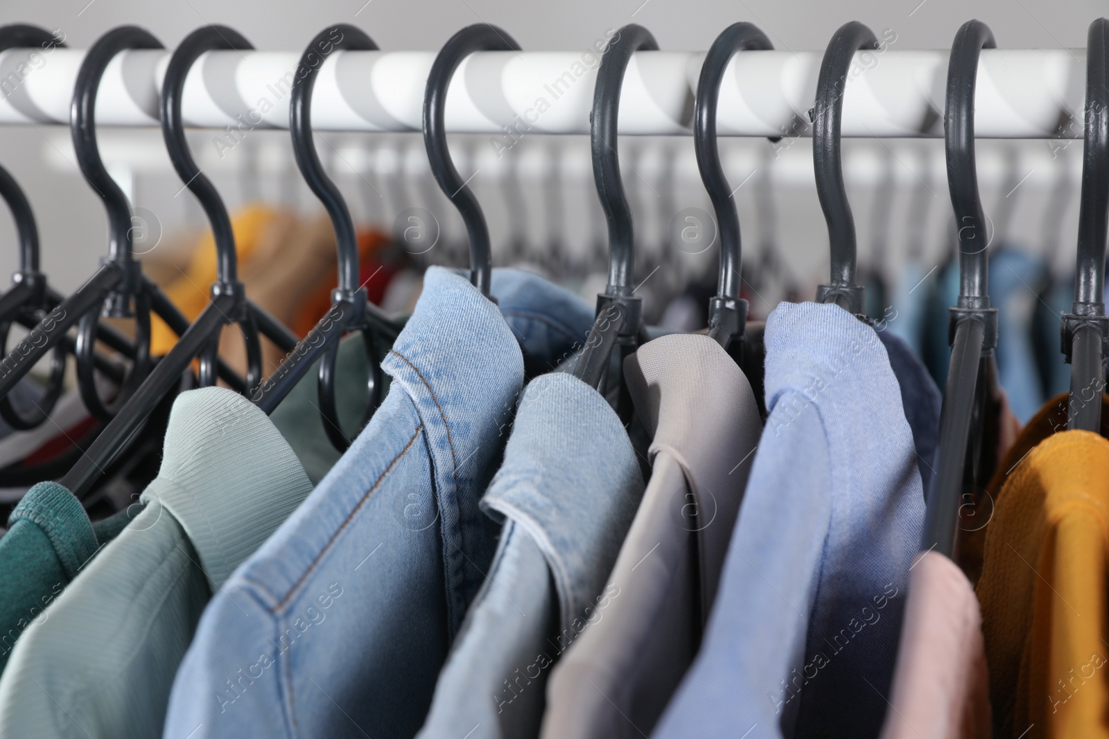 Photo of Rack with stylish clothes on blurred background, closeup. Fast fashion