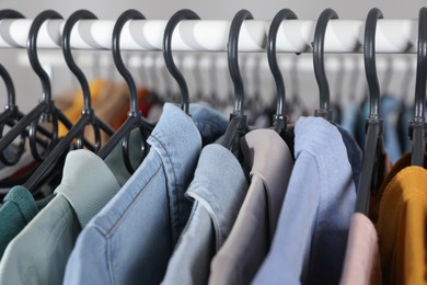 Rack with stylish clothes on blurred background, closeup. Fast fashion