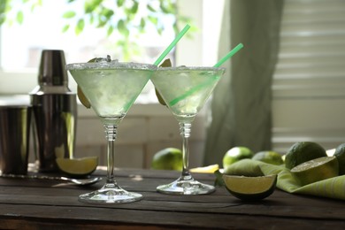 Photo of Delicious Margarita cocktail in glasses and lime on wooden table