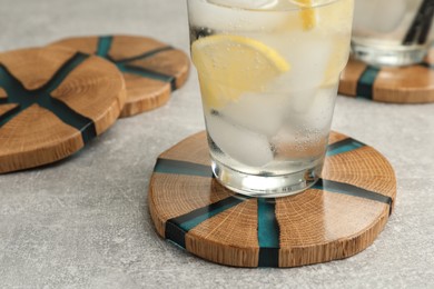 Photo of Cocktail and stylish cup wooden coasters on light grey table