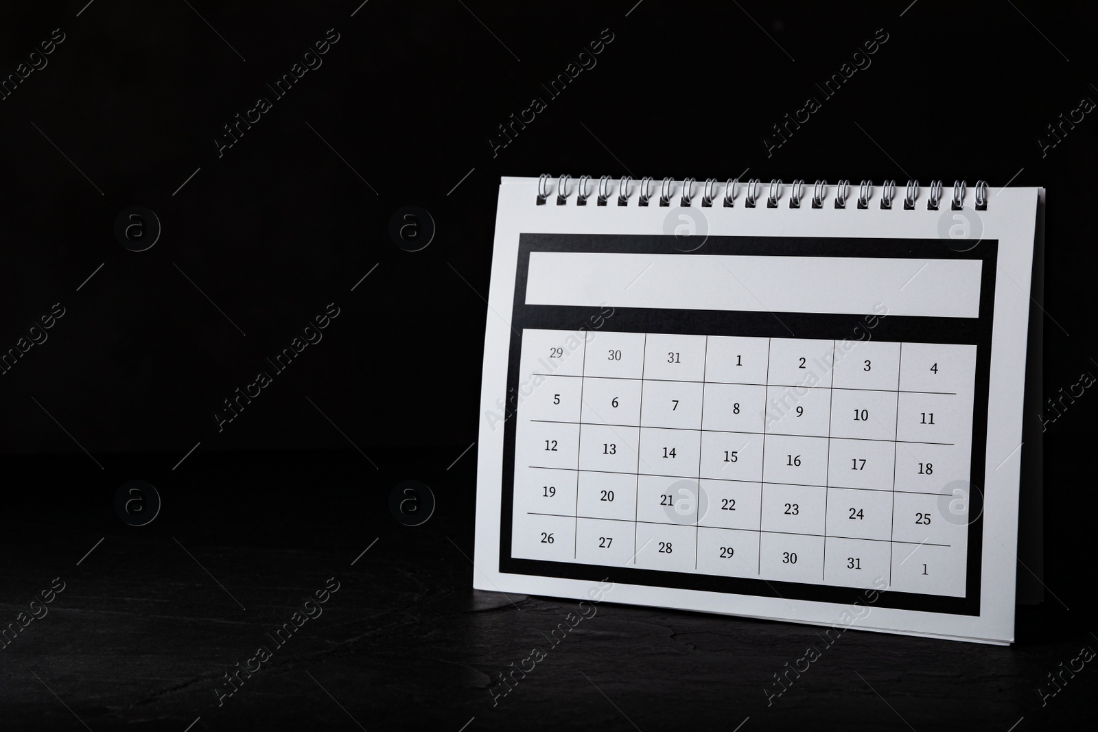 Photo of Paper calendar on black table, space for text. Planning concept