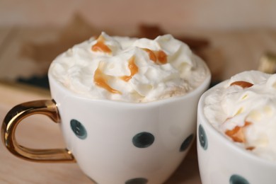 Photo of Delicious coffee with whipped cream and caramel syrup in cups, closeup