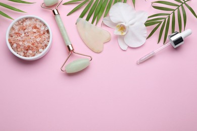 Photo of Flat lay composition with gua sha stone and face roller on pink background. Space for text