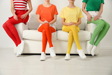 Photo of Women wearing bright tights sitting on sofa indoors, closeup