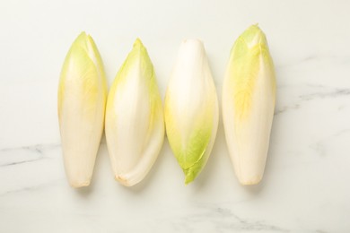 Raw ripe chicories on white marble table, top view